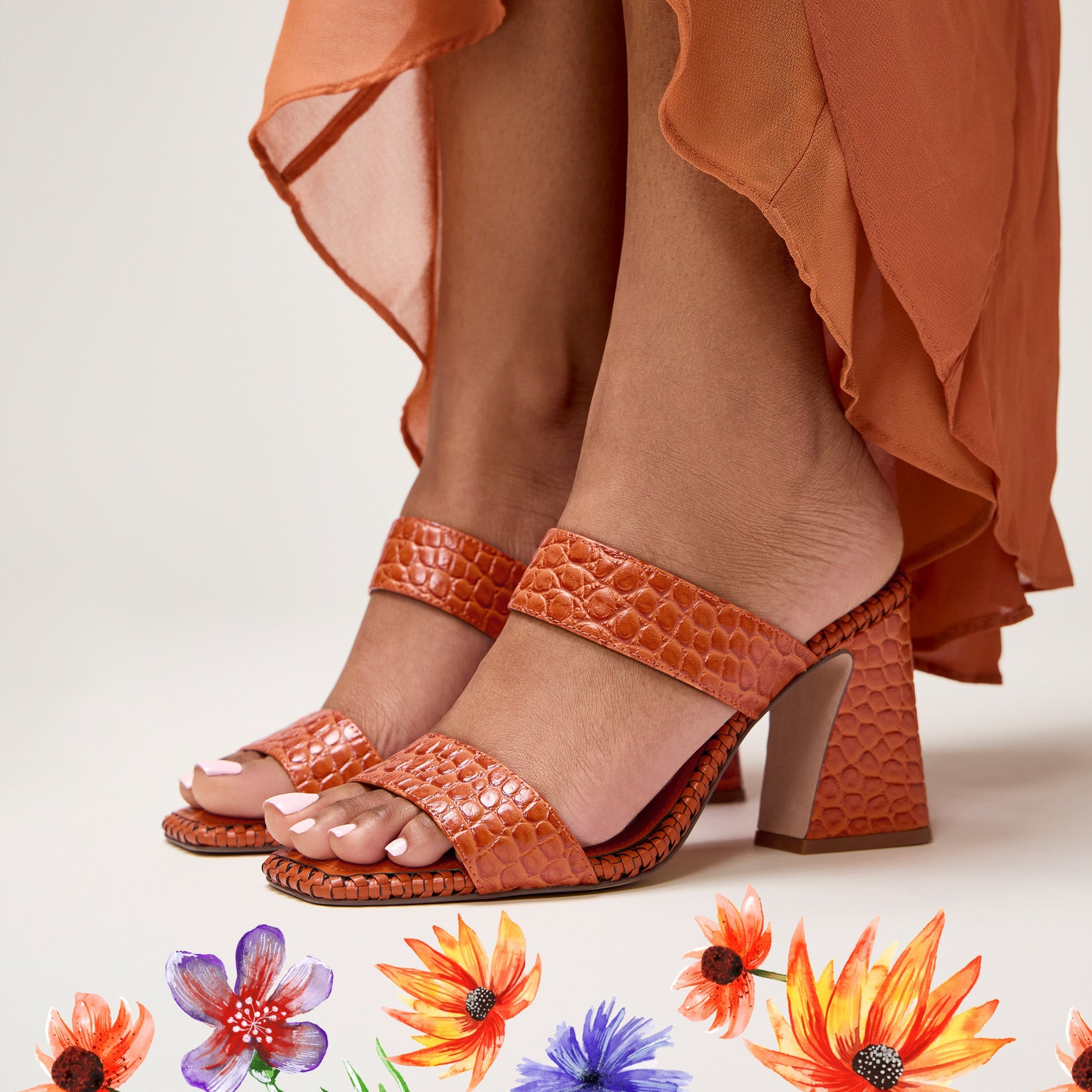 Orange high-heeled sandals worn with an orange skirt on a light background