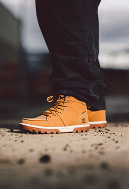Close-up shot of man in black pants and tan winter boots standing