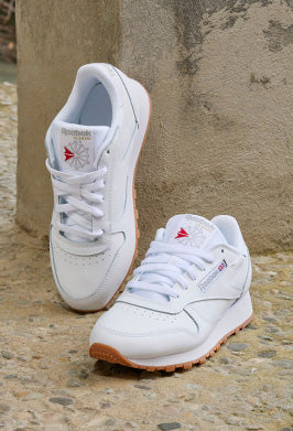 White sneakers with tan soles placed on stone background