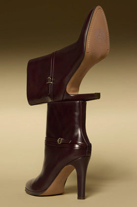 Mahogany ankle boots placed on a plain yellow background