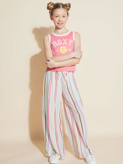 Child in a pink tank top with a "Roxy" logo and colorful striped pants