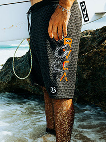 Close up of man in board shorts holding a white surfboard