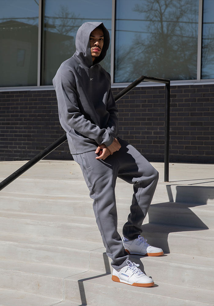 Man in gray sweat set and white sneakers standing on stairs