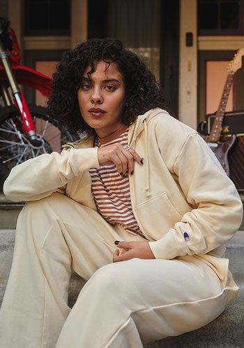 Woman in white outfit sitting outside in front of a building