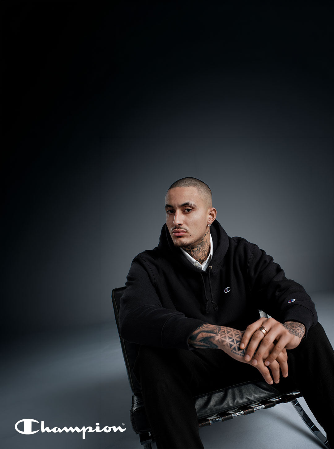 A person in black hoodie sitting against gray background