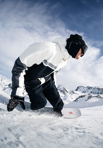Man snowboarding on a snowy mountain in black and white snow gear