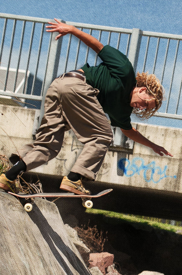 Man in green shirt and chino pants skateboarding